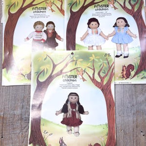 May include: Several vintage paper patterns for "Foster Children" dolls. The patterns feature illustrations of the dolls in various outfits, including a western outfit, a prairie dress, and other styles. The patterns include the doll's name and the price.