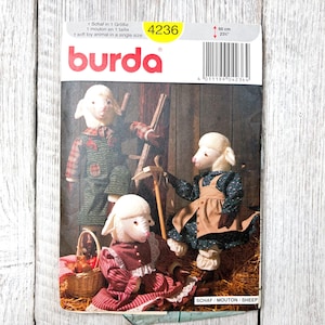 May include: A Burda sewing pattern featuring a soft toy sheep in a single size. The pattern includes instructions for creating three sheep dolls, each dressed in different outfits. The pattern's dimensions are 23 inches.