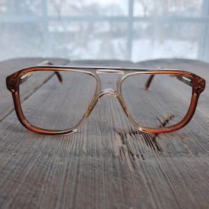 May include: A pair of clear, brown-rimmed glasses with a squared shape.