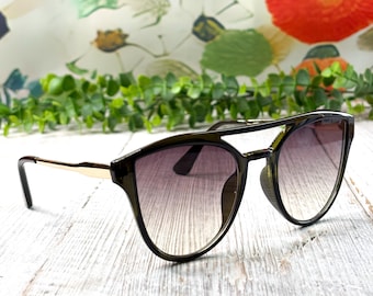 Gafas de sol redondas estilo aviador: plástico negro, metal dorado, lentes grises, protección UV400.