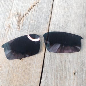 Puede incluir: Dos lentes de repuesto negras para gafas de sol. Las lentes son curvadas y tienen un tinte oscuro.