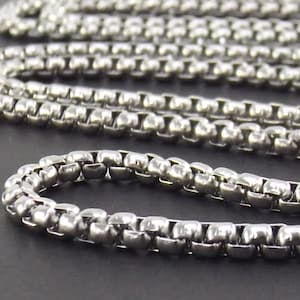 May include: A silver chain necklace with a box chain design. The chain is made of small, square-shaped links.