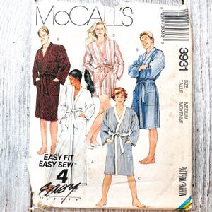 May include: A McCall's sewing pattern envelope for bathrobes, labeled 3931, size medium. The front displays illustrations of four individuals wearing different robe styles: a dark paisley print, a red striped robe, a solid blue robe, and a blue striped robe.