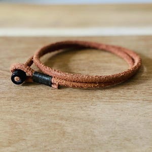 May include: A brown leather bracelet with a black bead accent.