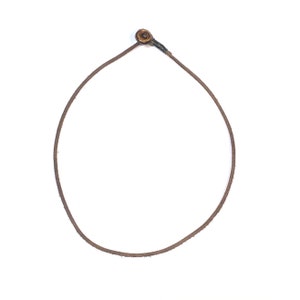 May include: A brown leather cord necklace with a gold-toned metal clasp.
