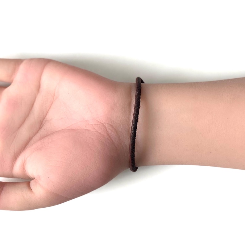 May include: A brown leather bracelet on a person's wrist.