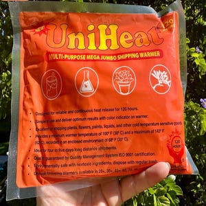 May include: An orange UniHeat multi-purpose shipping warmer package. The package has the text "UniHeat" and "MULTI-PURPOSE MEGA JUMBO SHIPPING WARMER". The package includes icons of a paint bucket, a flask, a potted plant, and a flower. The package is designed for reliable and continuous heat release for 120 hours.