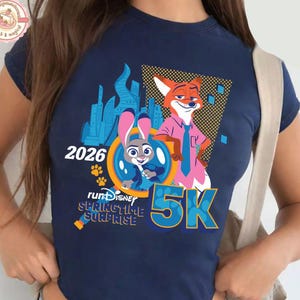 May include: A navy blue crop top with a graphic featuring Judy Hopps and Nick Wilde from Zootopia, the text "2026" and "5K". The design also includes the words "runDisney Springtime Surprise".