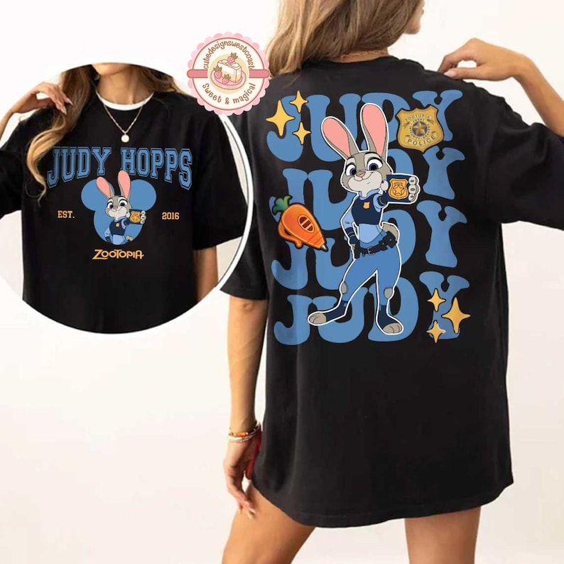 May include: Black t-shirt featuring Judy Hopps from Zootopia. The front design includes "JUDY HOPPS" in blue, a cartoon image of Judy, and "EST. 2016". The back displays "JUDY" repeated with Judy Hopps, a carrot, and police badge.