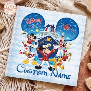 May include: A light blue Disney Cruise photo album with Mickey Mouse and friends. The cover features the words "Disney Cruise" and "Custom Name" in blue. The album has a nautical theme with a cruise ship illustration and the year 2020.