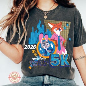 May include: Dark grey t-shirt with a graphic of Judy Hopps and Nick Wilde from Zootropolis, with the text "2026" and "5K". The design includes the words "runDisney Springtime Surprise".