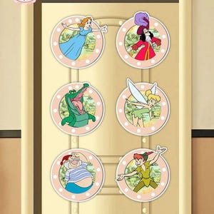 May include: Six circular stickers featuring characters from Peter Pan. The stickers depict Peter Pan, Wendy, Captain Hook, Tinkerbell, Mr. Smee, and a crocodile, set against a pink background with white polka dots.