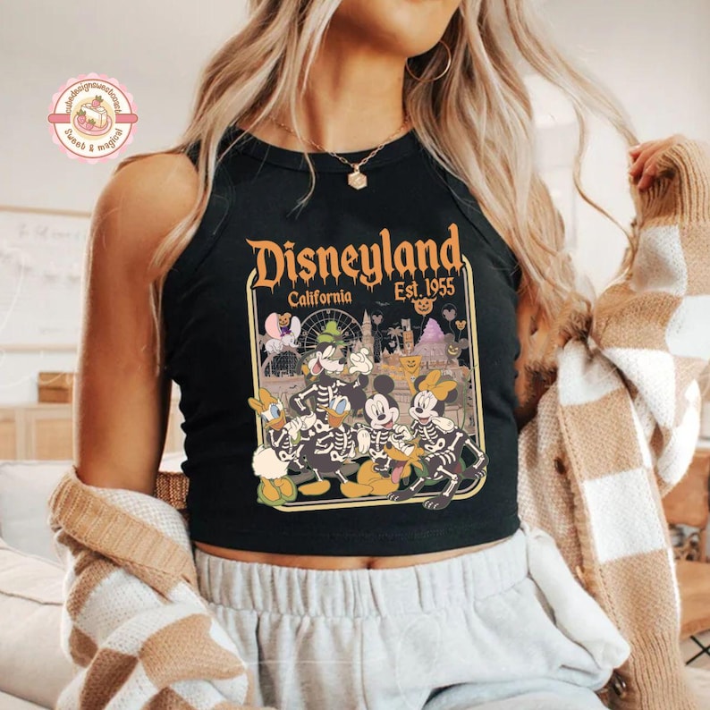 K&ouml;nnte beinhalten: Schwarzes Tanktop mit Disneyland-Grafik. Das Design zeigt Skelettversionen von Mickey Mouse, Donald Duck und Goofy mit dem Text "Disneyland California Est. 1955". Ein Halloween-Themen-Top.