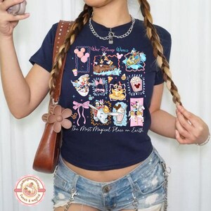 May include: Navy blue t-shirt featuring a colorful graphic of various Disney characters and attractions. The text "Walt Disney World" and "The Most Magical Place on Earth" are also displayed on the shirt. The shirt is paired with denim shorts.