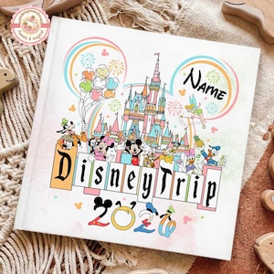 May include: White Disney Trip 2020 photo album featuring Disney characters, a castle, and the text "Disney Trip" and "Name". The album has a colorful design with balloons, fireworks, and a rainbow.
