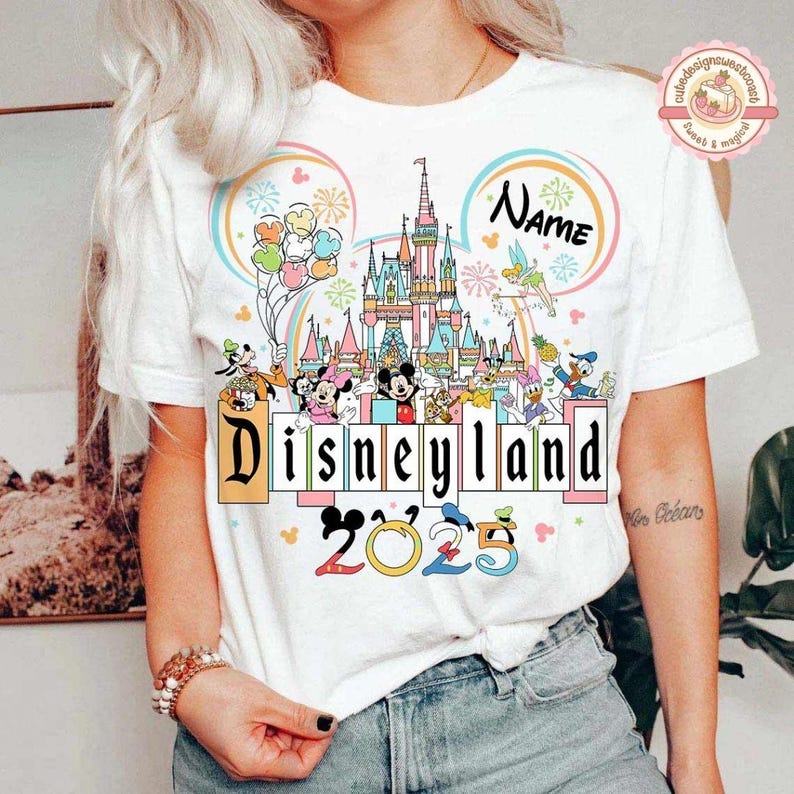 May include: White t-shirt with a colorful illustration of Disneyland, Mickey Mouse, and other Disney characters. The text "Disneyland" and "2023" are also included in the design. The text "Name" is included in the design.