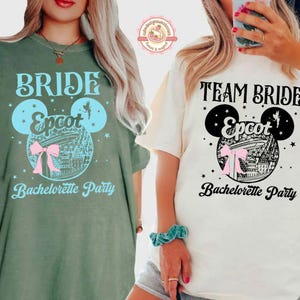 May include: Two t-shirts, one olive green and one cream, with "Bride" and "Team Bride" printed on them. Each shirt features a Mickey Mouse head design with "Epcot" and "Bachelorette Party" text. The design includes a pink bow and a depiction of a building.