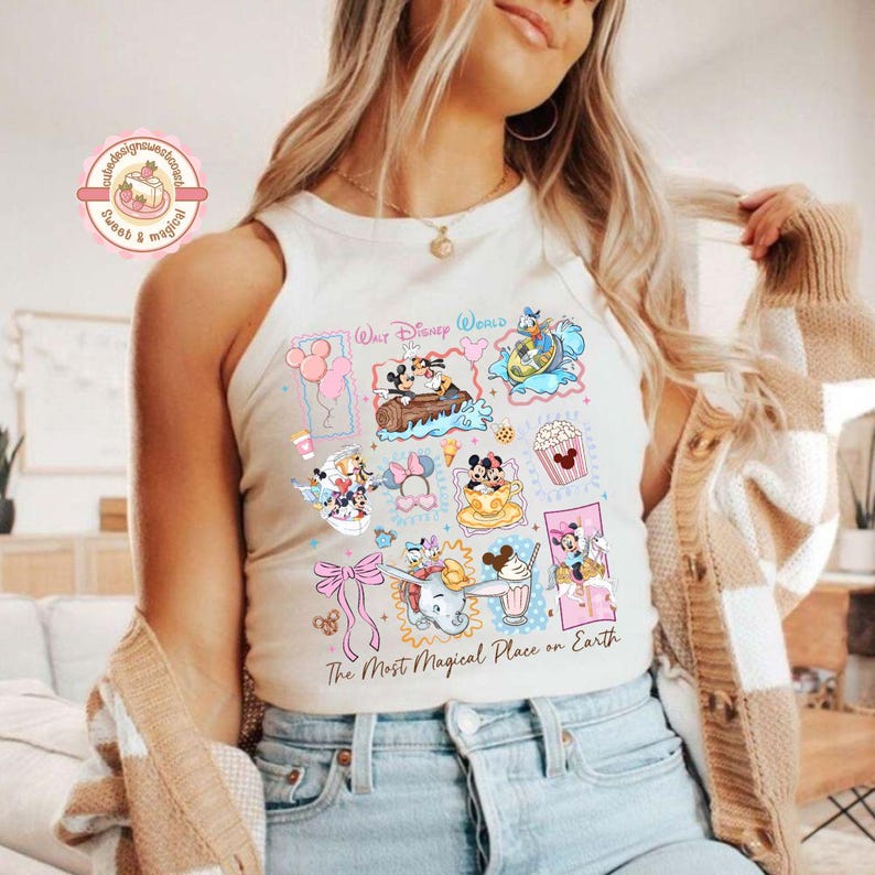 May include: Cream-colored tank top featuring colorful Disney World graphics. The design includes images of Mickey and Minnie Mouse, Donald Duck, Dumbo, and popcorn. Text on the shirt reads "Walt Disney World" and "The Most Magical Place on Earth."