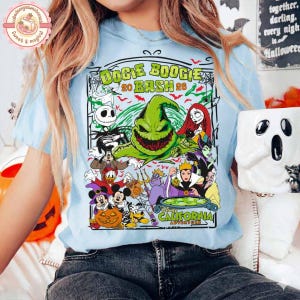 K&ouml;nnte beinhalten: Ein hellblaues T-Shirt mit einem Grafikdruck von Oogie Boogie und verschiedenen Disney-Figuren in einer Halloween-Szene. Der Text lautet Oogie Boogie Bash 2024 California Adventure. Das Design enth&auml;lt K&uuml;rbisse, Spinnennetze und Flederm&auml;use.