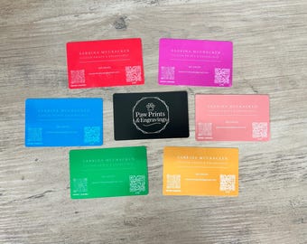 May include: A selection of business cards in shades of red, pink, blue, green, and orange. Each card displays "Sabrina McCracken" and contact details. A black card with "Paw Prints & Engravings" is also visible.