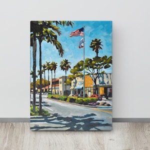 May include: An oil painting on canvas depicts a sunny street scene with palm trees, buildings, and an American flag waving in the sky. The artwork features a vibrant color palette with blue, green, yellow, and brown hues, capturing a sense of a warm day.