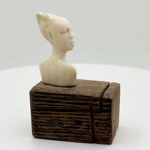 Busto pequeño de mujer africana (1,5" x 1") sobre un trozo de madera (1,75" x 1,375" x 1,125"), década de 1960
