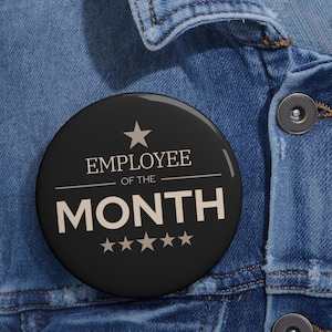 May include: A black circular badge featuring the words "EMPLOYEE OF THE MONTH" in white, a star, and five smaller stars. The badge is set against a blue denim jacket.