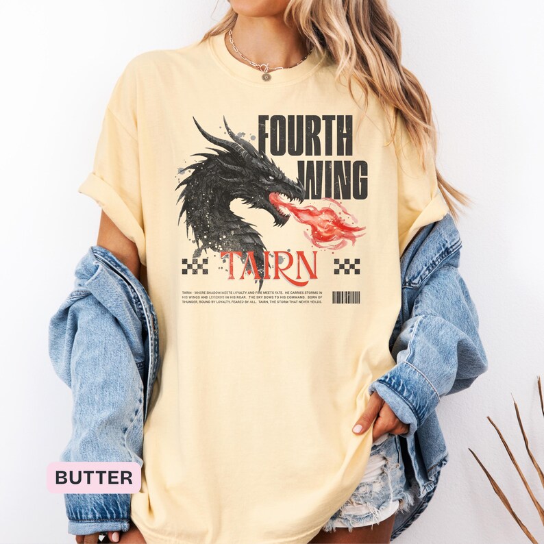 K&ouml;nnte beinhalten: Hellgelbes T-Shirt mit einem schwarzen Drachen, der rote Flammen speit, mit dem Text "FOURTH WING" dar&uuml;ber und "TARN" darunter. Das Shirt hat eine lockere Passform und kurze &Auml;rmel.
