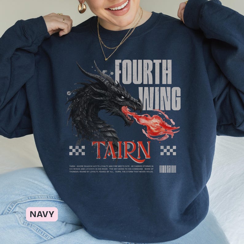 K&ouml;nnte beinhalten: Marineblaues Sweatshirt mit einem schwarzen Drachen, der Feuer speit. Die Worte "FOURTH WING" und "TAIRN" sind auf der Vorderseite aufgedruckt. Zus&auml;tzlicher Text und ein Barcode sind ebenfalls vorhanden. Ein Grafik-T-Shirt.