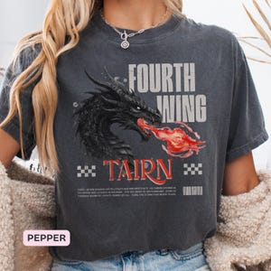 K&ouml;nnte beinhalten: Dunkelgraues T-Shirt mit einem schwarzen Drachen, der rotes Feuer speit, mit den Worten "FOURTH WING" und "TAIRN" in Wei&szlig;. Das Shirt hat einen Vintage-Look mit kleinen Texten am unteren Rand.