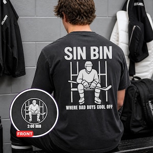 May include: Black t-shirt with the text "SIN BIN" and a graphic of a hockey player sitting in a penalty box. The phrase "WHERE BAD BOYS COOL OFF" is printed below the graphic. A circular graphic on the bottom left shows the front design.