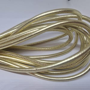 Può includere: Primo piano di un cordoncino dorato, che mostra la trama e la lucentezza del materiale.