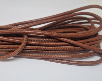 May include: A close-up of a brown leather cord. The cord is coiled and has a textured surface.