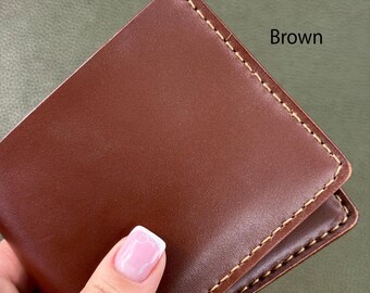 May include: A brown leather wallet with visible stitching. The word "Brown" is printed on the top right corner of the image. The wallet is held by a person.