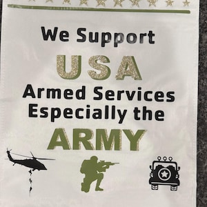 May include: A white rectangular garden flag featuring the text We Support USA Armed Services Especially the ARMY in black and gold glitter. The design includes a row of gold glitter stars at the top and bottom, a black helicopter, a soldier, and a jeep.