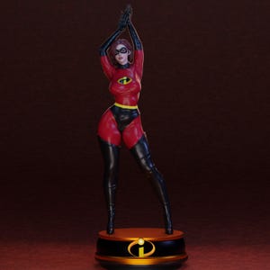 May include: A figurine of a female superhero in a red and black bodysuit with a yellow belt. The figure has black gloves, boots, and a mask. The base is black with a gold emblem.