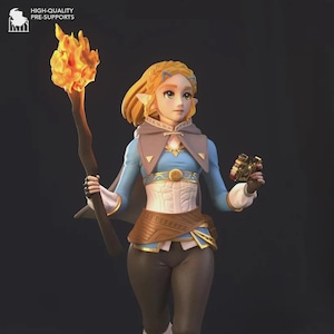 Op de afbeelding: Gedetailleerd beeldje van een personage uit een fantasy-videogame. Het figuur draagt een blauw-witte outfit met een bruine riem en cape. Ze houdt een fakkel met een helder oranje vlam en een klein gouden voorwerp vast.