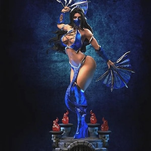 Puede incluir: Estatua detallada de una guerrera con un atuendo azul, sosteniendo abanicos. La figura está posada dinámicamente, con cabello negro largo y una máscara. La base presenta calaveras y llamas, con un fondo azul oscuro.