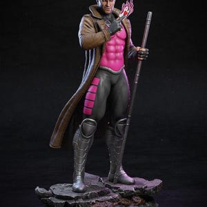 May include: A detailed figurine of the Marvel Comics character Gambit. The figure is posed with a staff and a playing card engulfed in pink energy. He wears a brown trench coat, black and pink suit, and armored boots. The base is a rocky terrain.