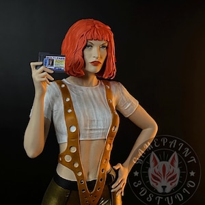 May include: A figurine of a woman with red hair holding a "MULTIPASS" card. She wears a white top, brown suspenders, and gold trousers. The background is black. The figurine is a collectible item.
