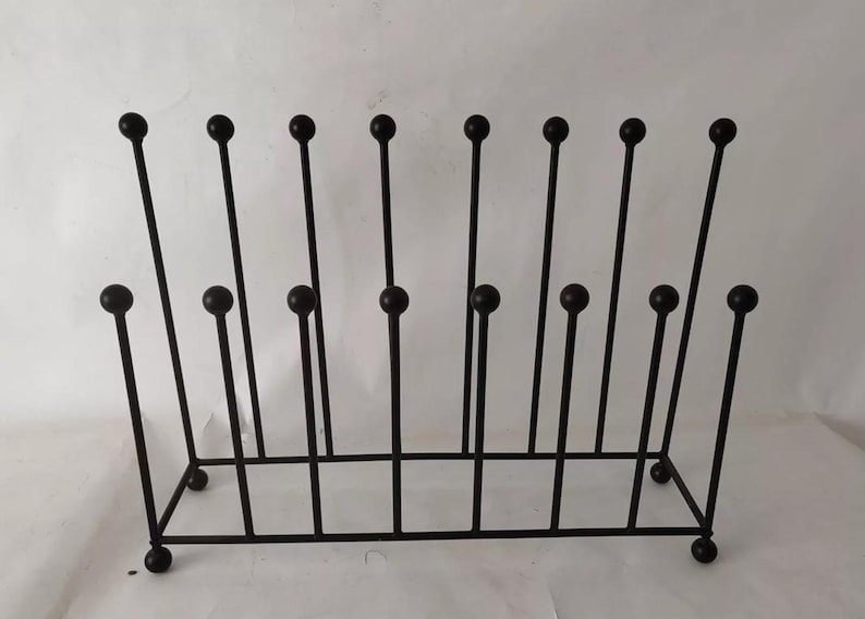 May include: A black metal boot rack with a rectangular base and vertical rods topped with round spheres. The rack has a series of vertical rods, some with a sphere in the middle, and is designed to hold multiple pairs of boots.
