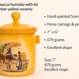 Może przedstawiać: Bursztynowo-żółty ceramiczny humidor na tytoń z pokrywką. Ręcznie malowana scena przedstawia powóz konny i ludzi. Humidor ma 17.78 cm wysokości i 15.24 cm szerokości i waży 679 gramów.