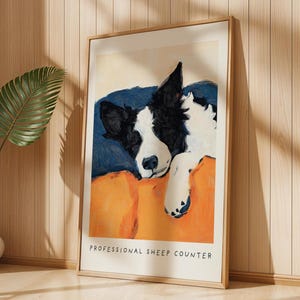 Framed Border Collie dog art print with orange and blue background, displayed on wooden wall with tropical leaves – modern pet wall art.