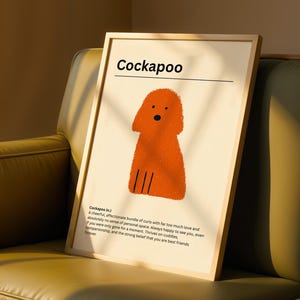 May include: A framed print featuring the word "Cockapoo" above an orange illustration of a dog. The print includes a definition of the dog breed. The artwork is displayed on a green sofa.