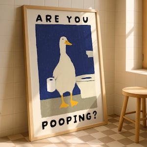 May include: Framed art print featuring a whimsical illustration of a white duck with yellow feet and beak, holding a roll of toilet paper. The text "ARE YOU POOPING?" is displayed in bold, black letters.