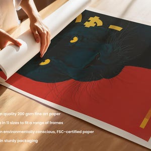 May include: A rolled art print featuring a stylized black panther with yellow eyes and gold accents against a red background. The print is being unrolled on a wooden surface. The print is on quality 200 gsm fine art paper.