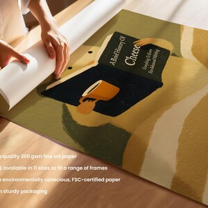 May include: Art print depicting a person reading "A Brief History of Cheese" with a cup. The print has a warm colour palette with a dark blue book and a yellow cup. The print is on fine art paper.