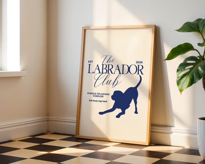 Puede incluir: Un p&oacute;ster enmarcado con fondo beige claro y texto y gr&aacute;fico azul marino. El texto dice "The Labrador Club" con la silueta de un perro labrador. El texto adicional incluye "Puddle splashing forever" y "Eat hard, nap hard."