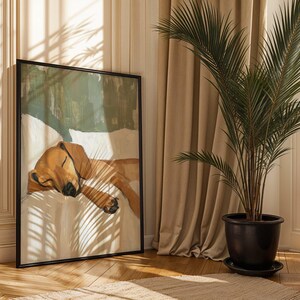 Peut inclure: Une peinture encadr&eacute;e d'un chien brun dormant sur un lit blanc. La peinture est dans un cadre noir et est accroch&eacute;e &agrave; un mur dans une pi&egrave;ce avec des rideaux beiges et un palmier en pot.