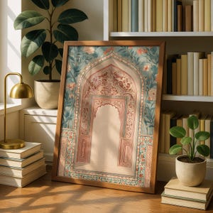May include: A framed print featuring an ornate archway design with floral and geometric patterns in shades of red, pink, and teal. The artwork is set in a wooden frame and leans against a wall near a bookshelf and plants.